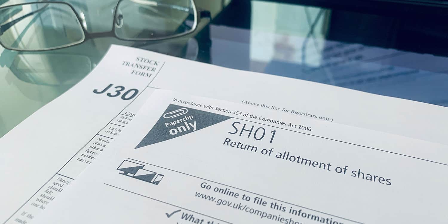 Image of Companies House form SH01, the Return of allotment of shares, and the J30 Stock transfer form lying on a desk. One or both of these forms may be required when you add company shareholders after incorporation.