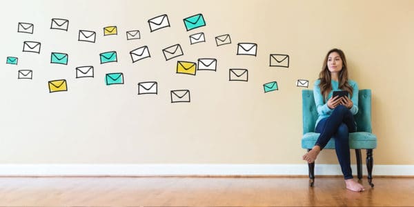Young woman sitting on a chair with digital letters floating along the wall beside her, illustrating the concept of a digital mailroom.