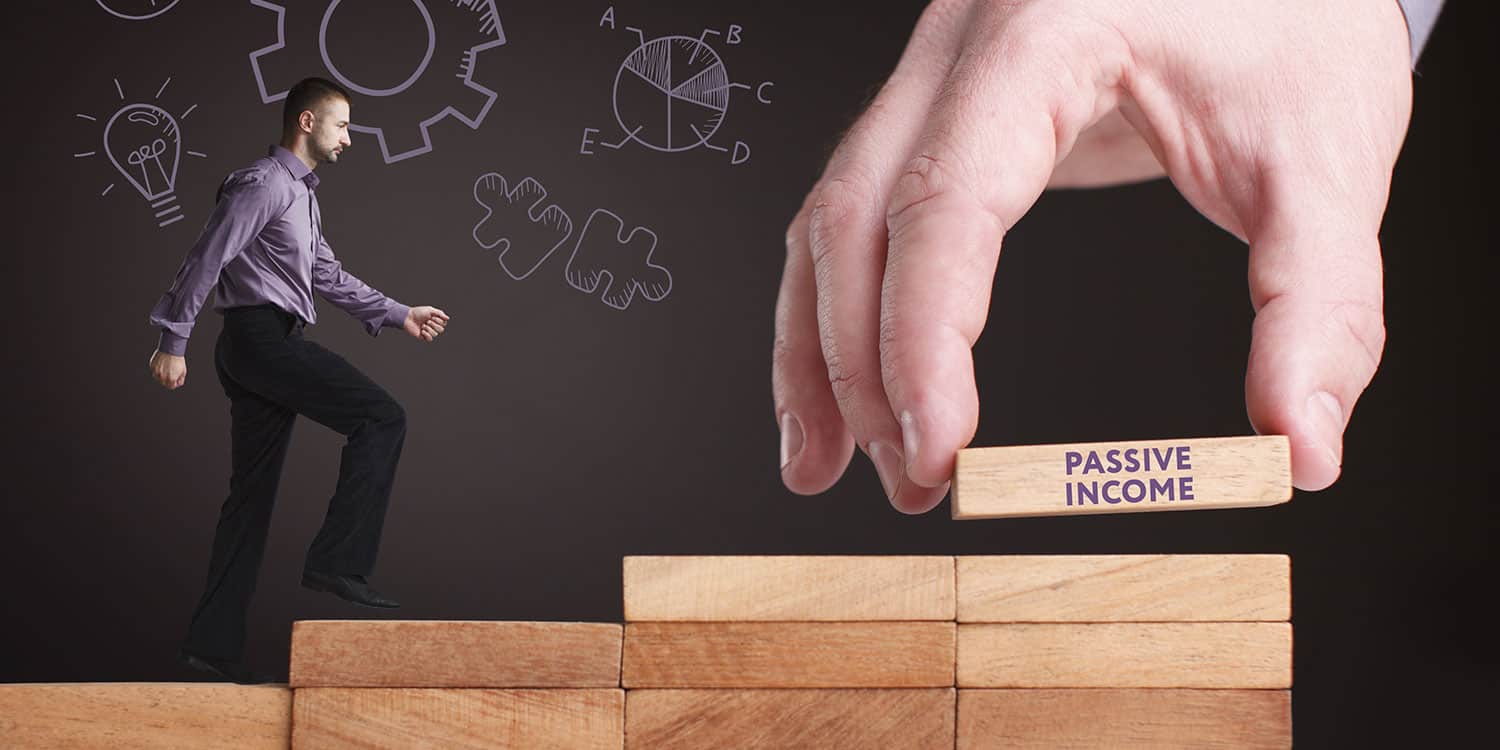 A man walking up stacks of wooden blocks set up like a staircase, with a giant hand placing a final block on the top with the words "passive income" stamped along the edge.