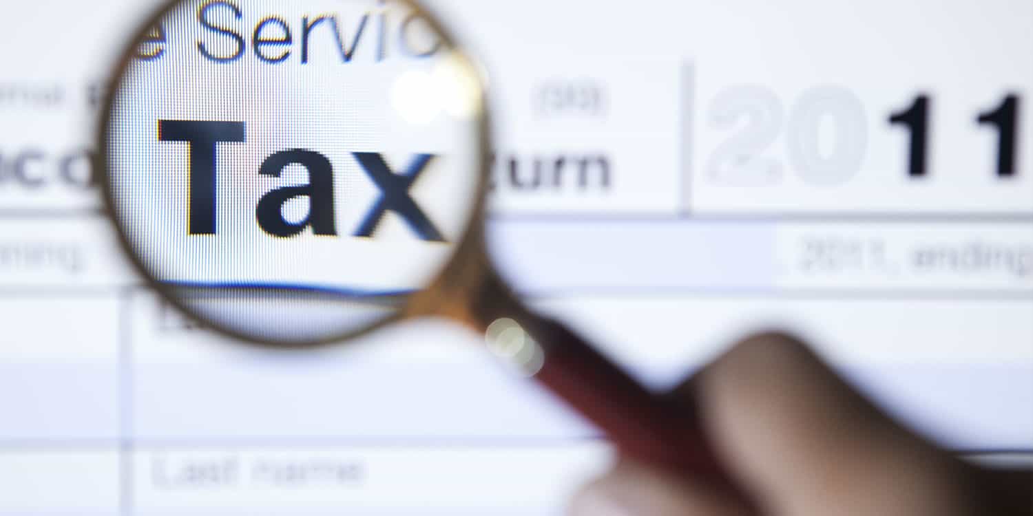 Magnifying glass held over a government form enlarging the word 'Tax', illustrating the importance of the UTR number.