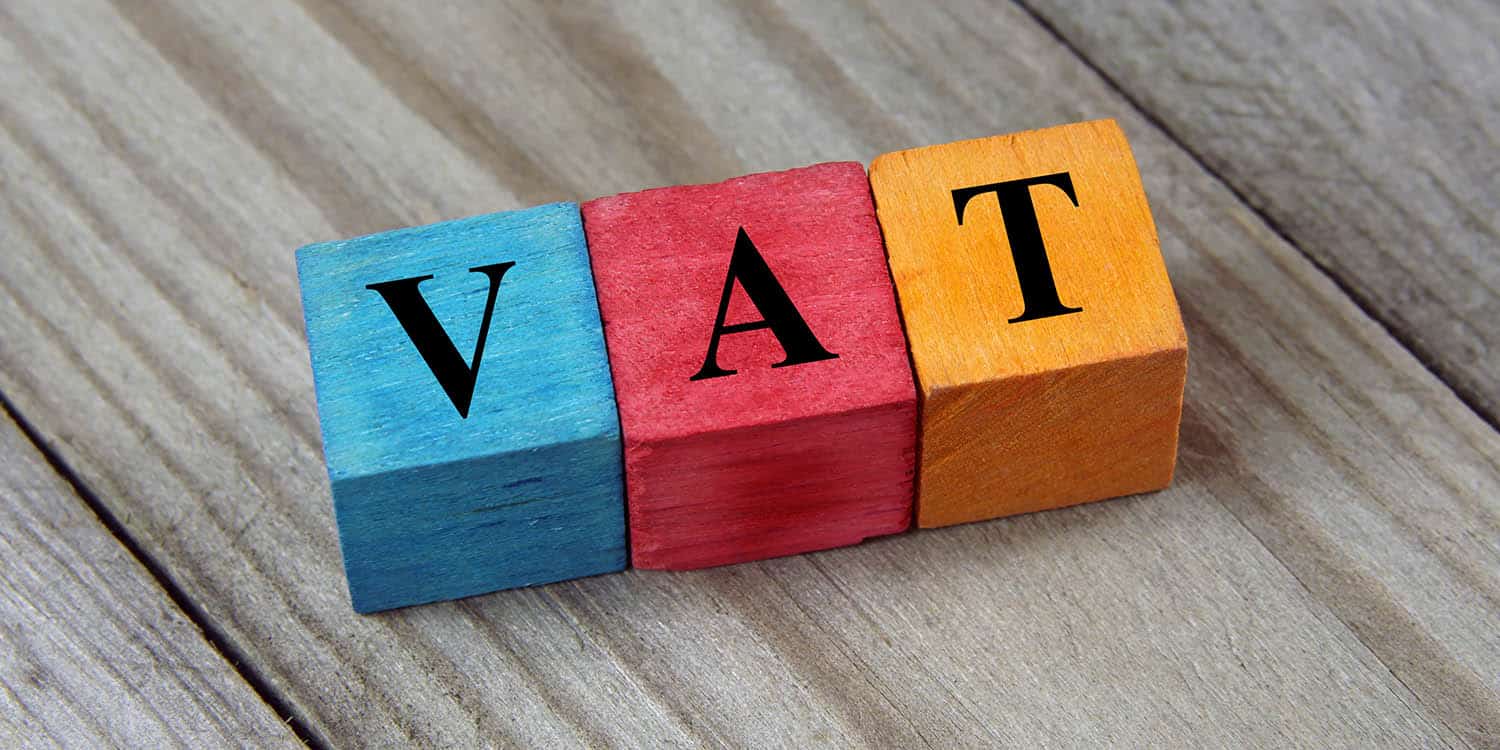 Three coloured wooden blocks, each with a letter in black capitals, spelling the word 'VAT.'