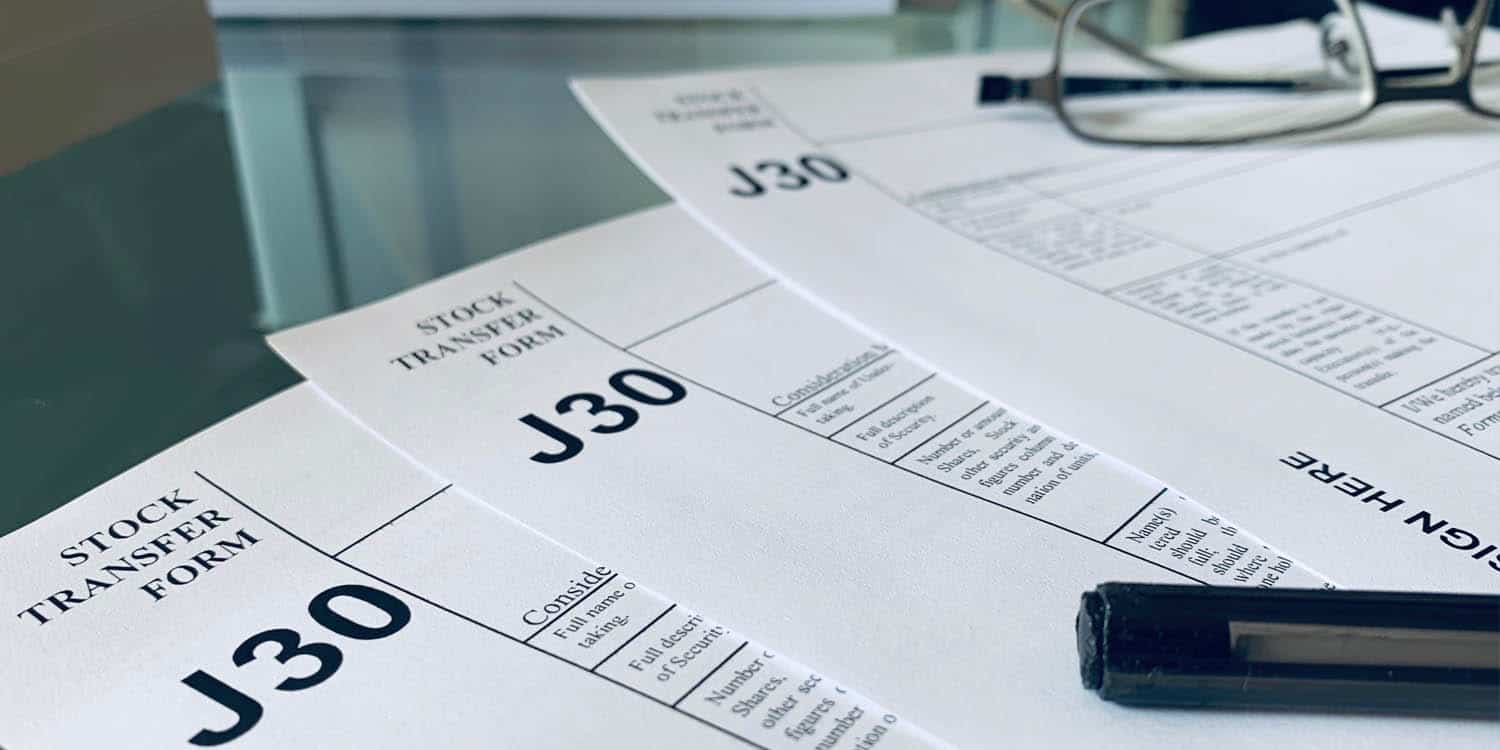 Image of three J30 Stock Transfer Forms placed on top of a glass table.