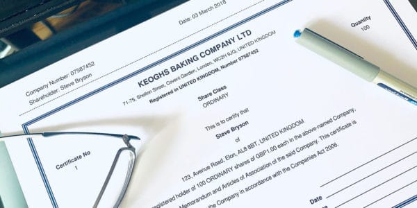 Share certificate on desktop with pen and pair of spectacles - a document you would receive if had shares in a company.