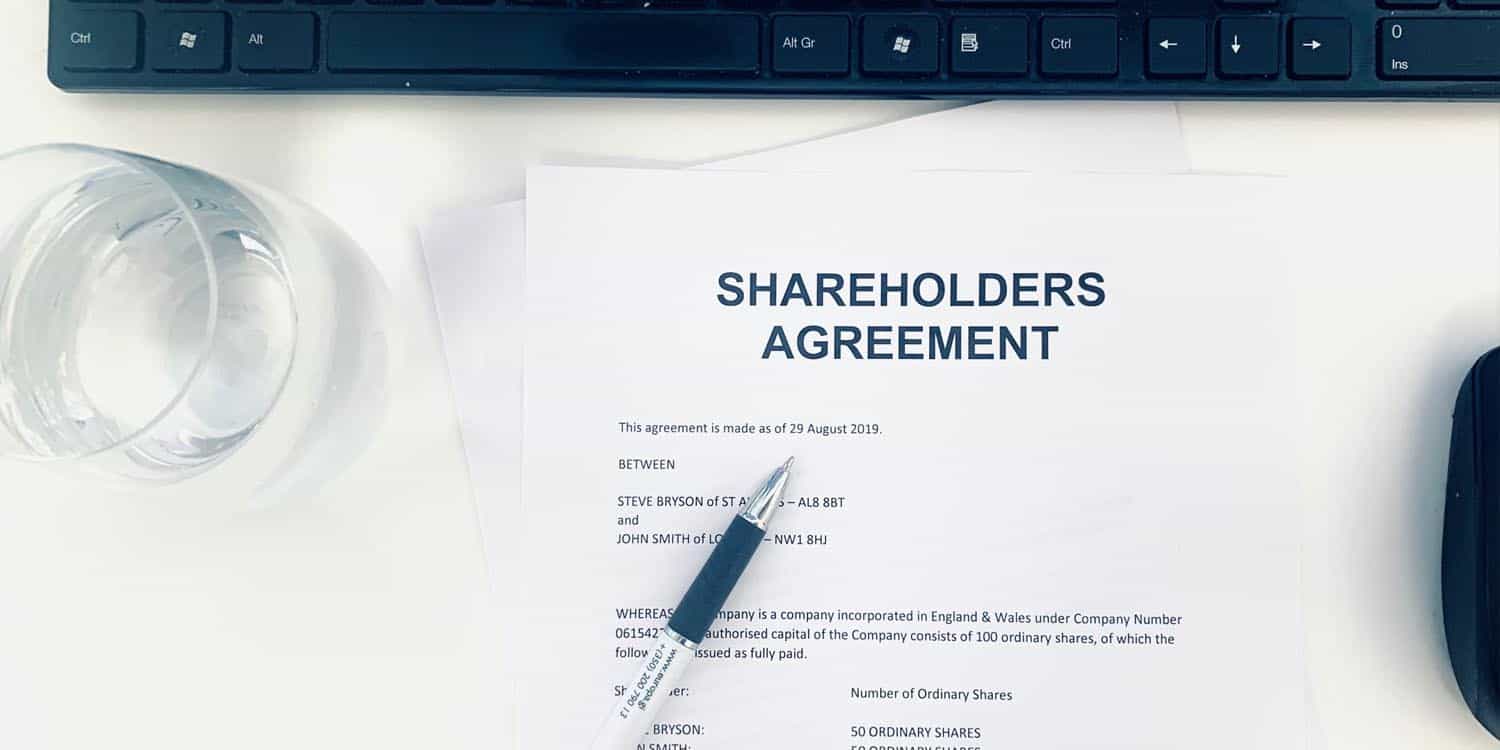 A shareholders' agreement document on a white desk.