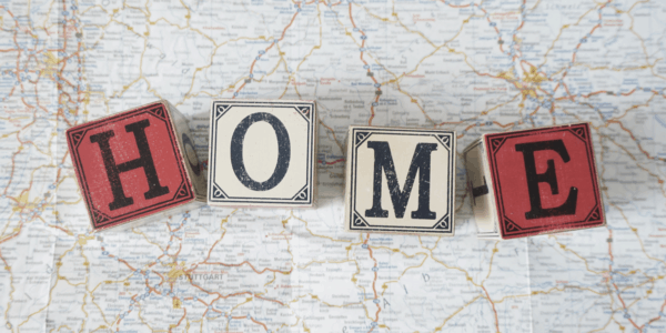 Four wooden blocks each with one letter spelling the word 'HOME' lying on top of a map - symbolising you can use your home address as a registered office?