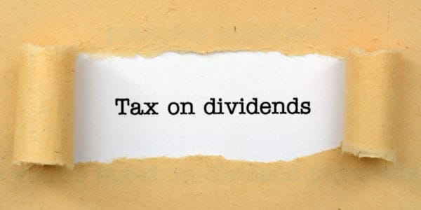 Image of a brown paper torn open in the middle to reveal the words "Tax on dividends" printed in black ink.