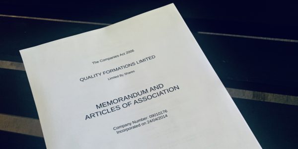 Image of a printed copy of articles of association lying n a glass tabletop.