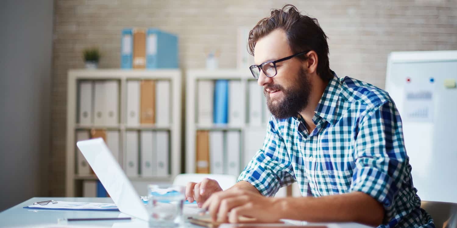 Image of a man sitting at a desk, working on a laptop, illustrating that certain administrative tasks must be completed after you set up a company.