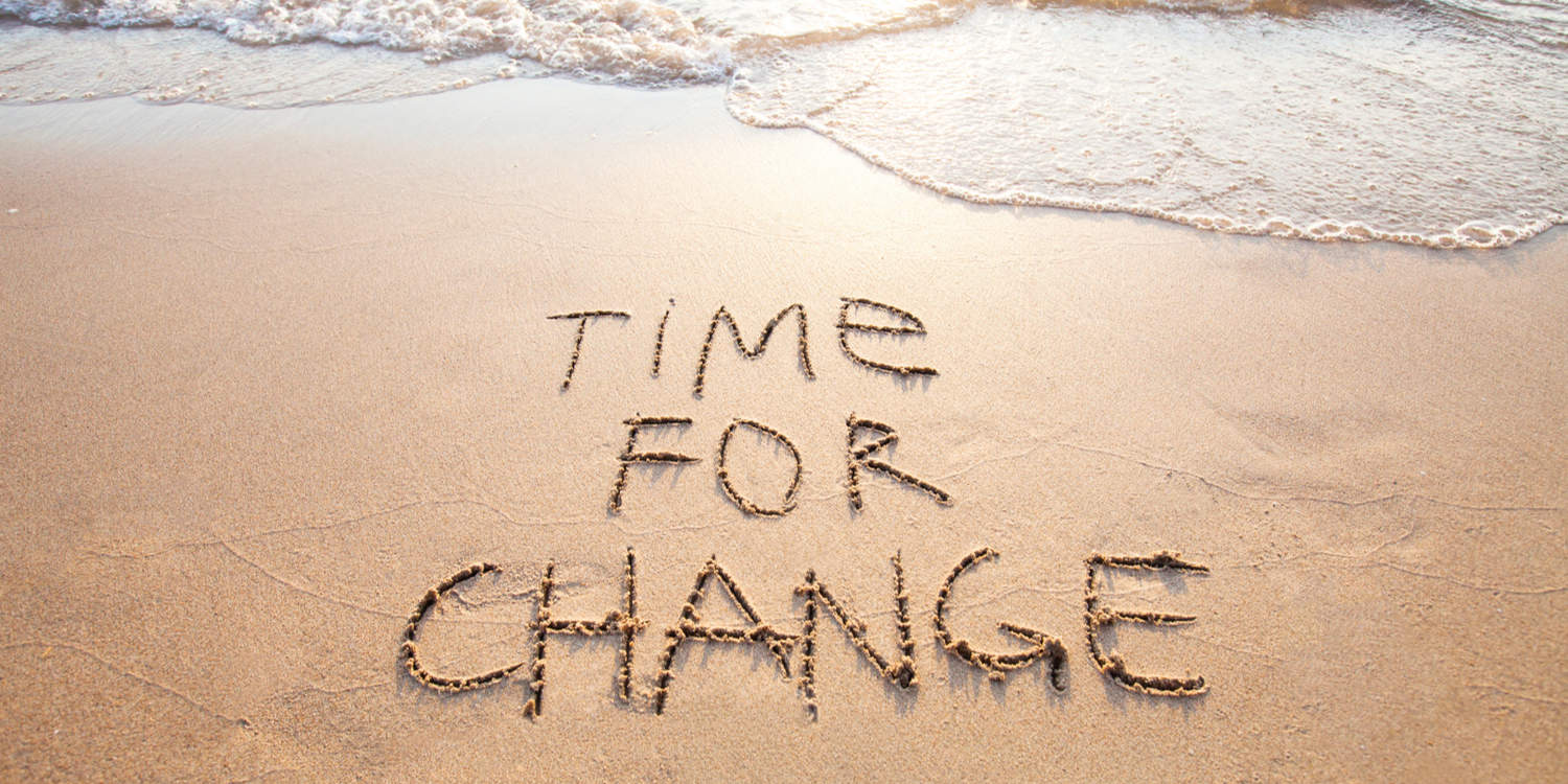 Photograph of a beach with the words 'Time for Change' written in the wet sand, representing the concept of changing your company name.