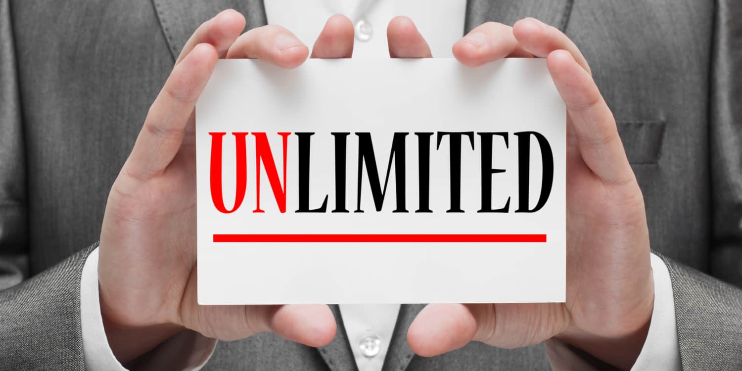 Photograph of a business person holding up a white card which displays the text 'UNLIMITED' in red and black print, representing the unlimited company structure.