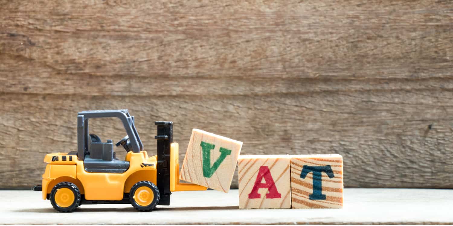 Image of toy forklift truck moving 3 wooden blocks each with the letters V, A and T displayed on them, depicting the concept of VAT registration.