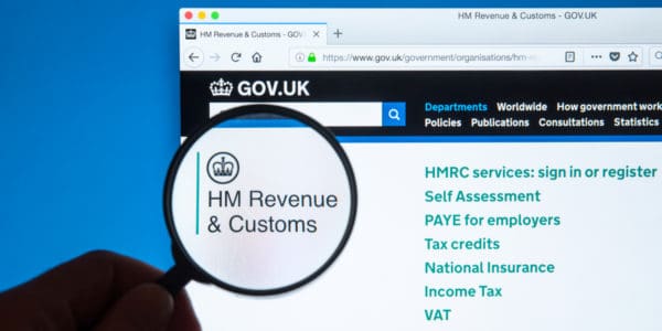 GOV.UK website with magnifying glass held over the heading 'HM Revenue & Customs' to add focus and make larger.