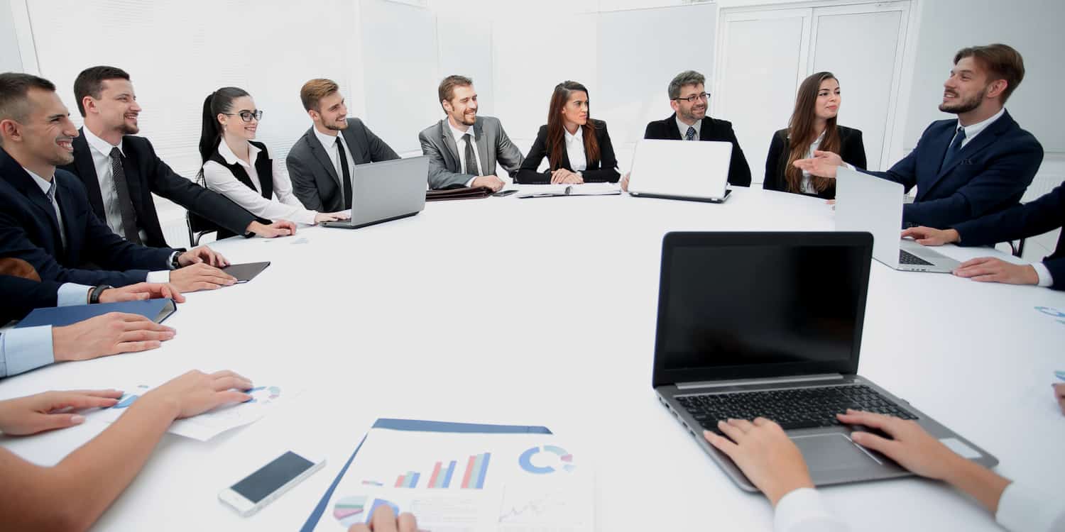 Board of Directors Meeting with 10 individuals sitting around a large, white boardroom table.