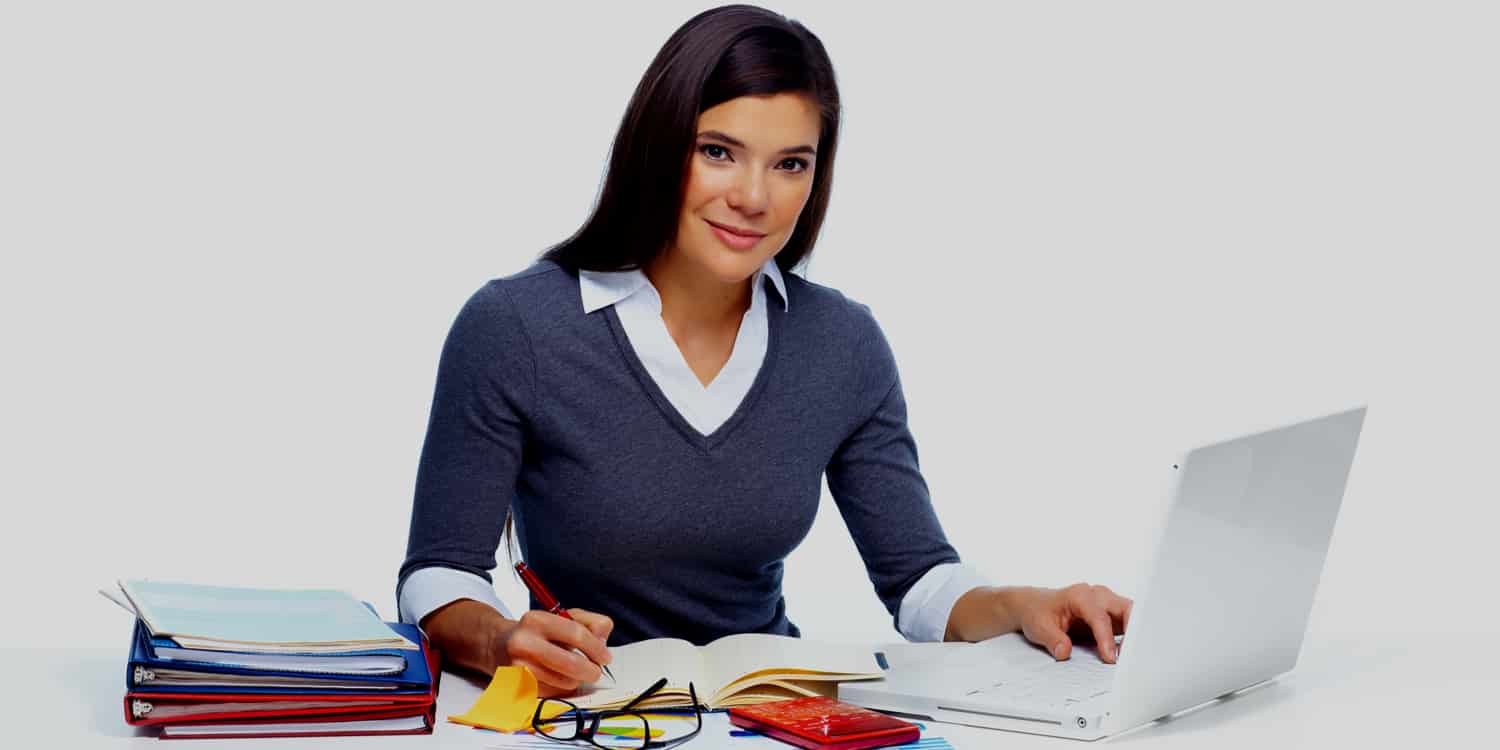 Business woman sitting at desk with laptop, calculator and paperwork preparing annual accounts.