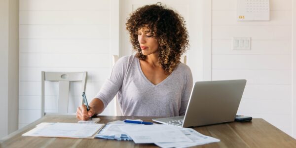 A small business owner works through paperwork at her table as she figures out how to pay herself.