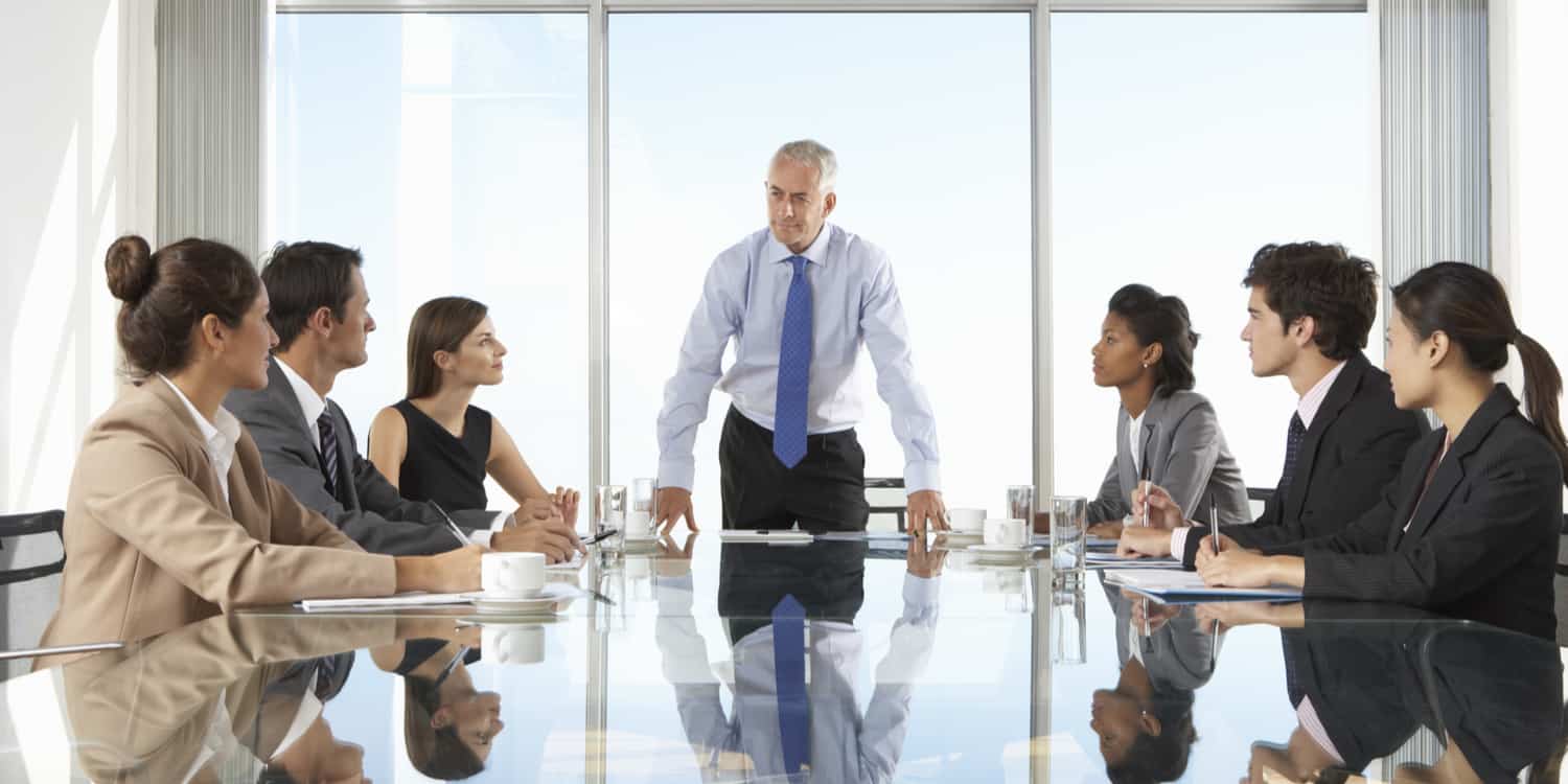 Shareholders attending a general meeting in a modern office with a glass meeting table.