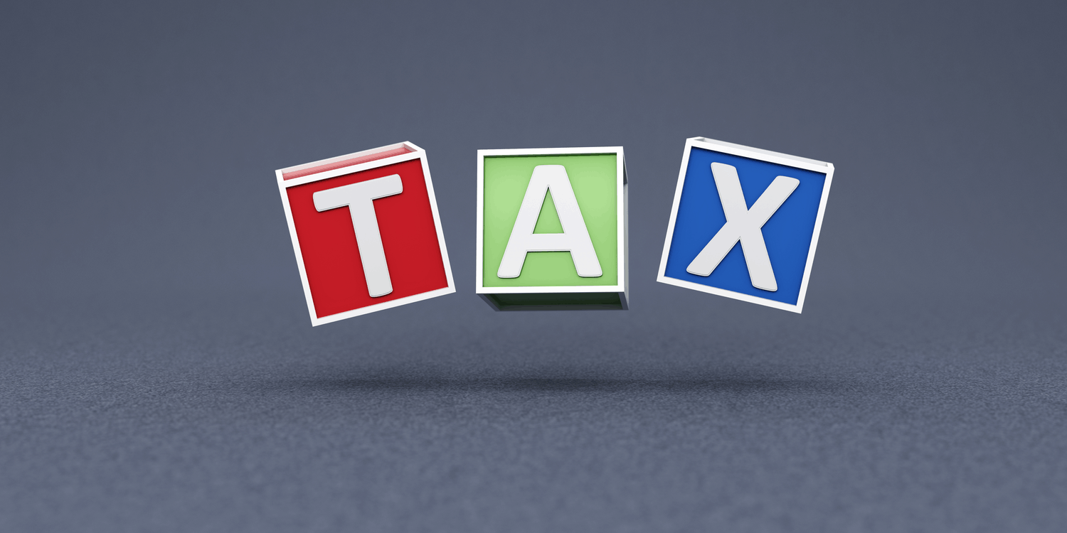 Three coloured cubes each with a letter in white font spelling the word TAX.