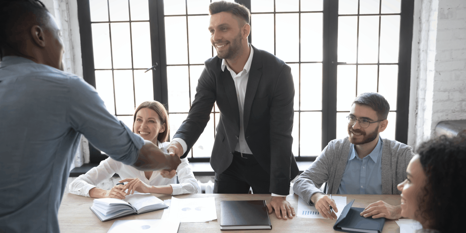 Smiling company director in suit shaking hands welcoming a new director at a board meeting - illustrating the concept of company director appointment.