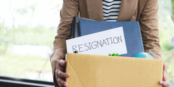 Businesswoman with resignation letter, packing up all her personal belongings and files into a brown cardboard box.
