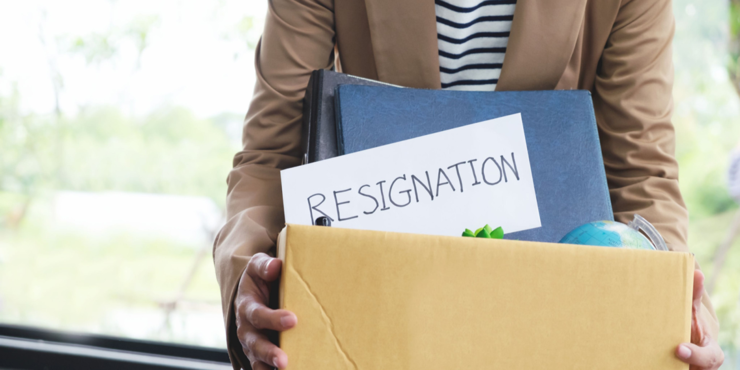 Businesswoman with resignation letter, packing up all her personal belongings and files into a brown cardboard box.