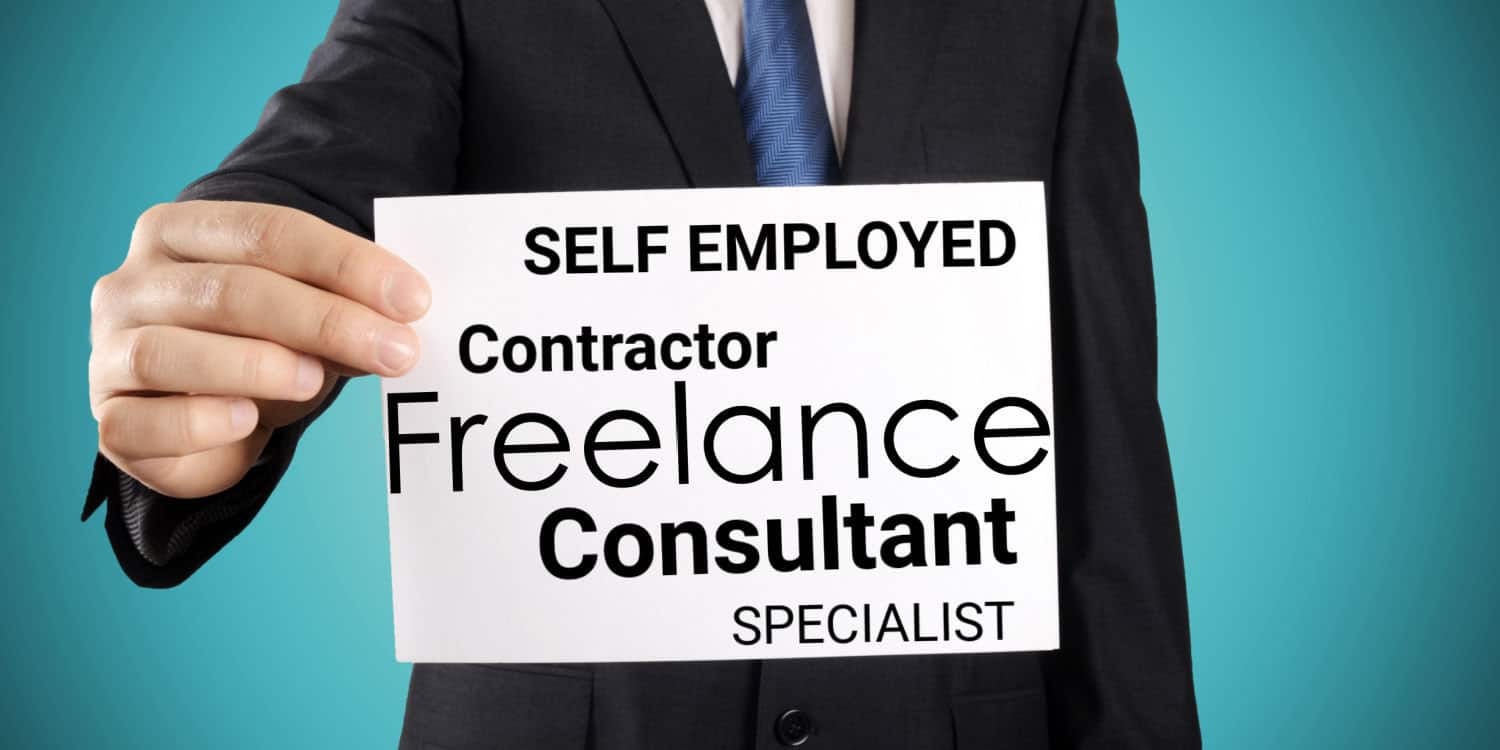 Businessman holding a white card with the following words in black text: Self-employed, Contractor, Freelance, Consultant, Specialist. These being, who would use a personal service company.