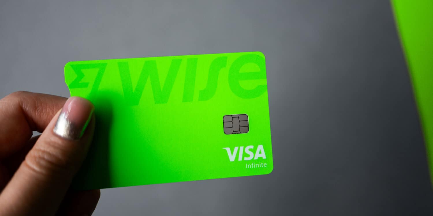 The Wise Business Account card held by a female hand against a light grey background.