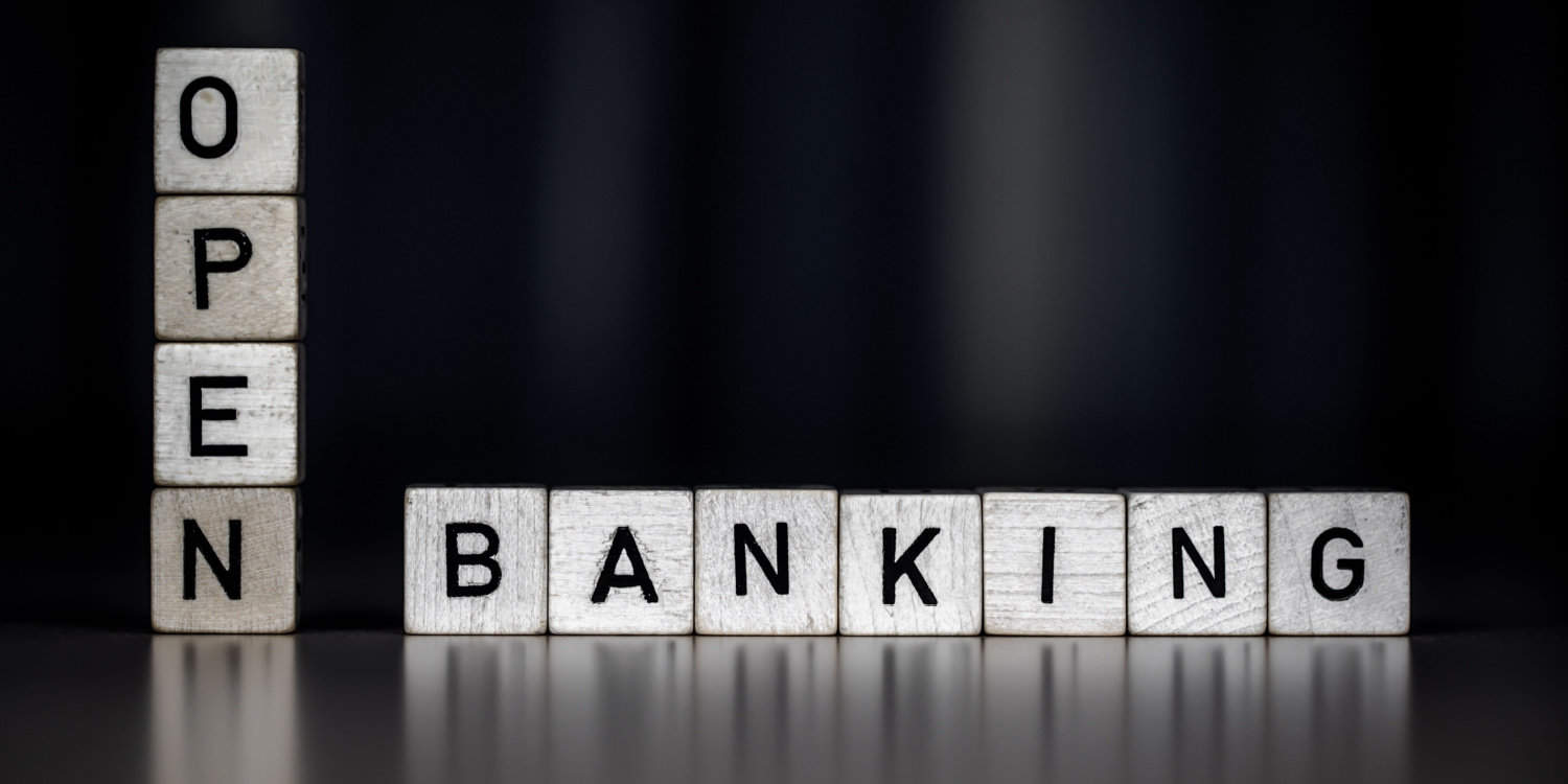 The word OPEN BANKING on white wooden cubes, with dark grey background.