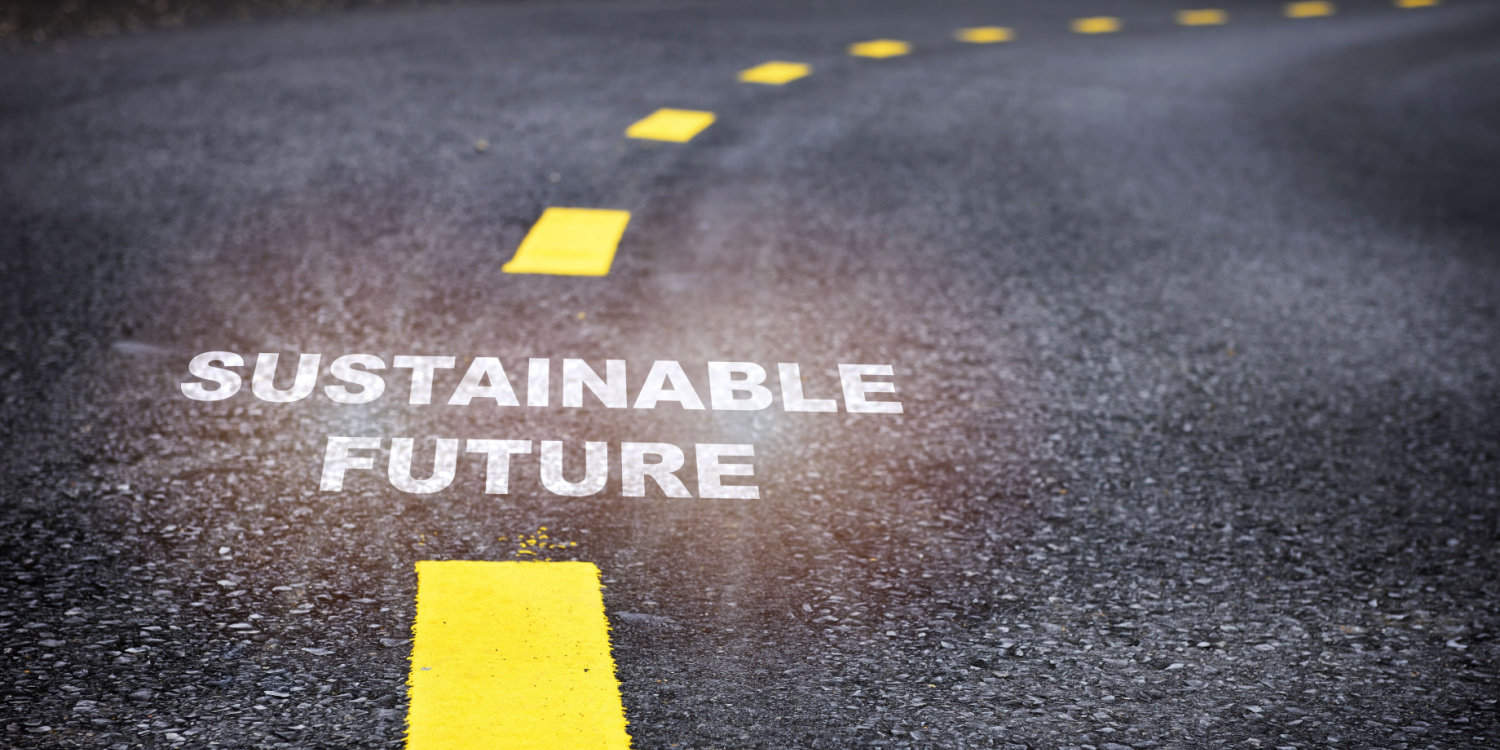 'Sustainable future' written on an asphalt road surface with yellow marking lines.