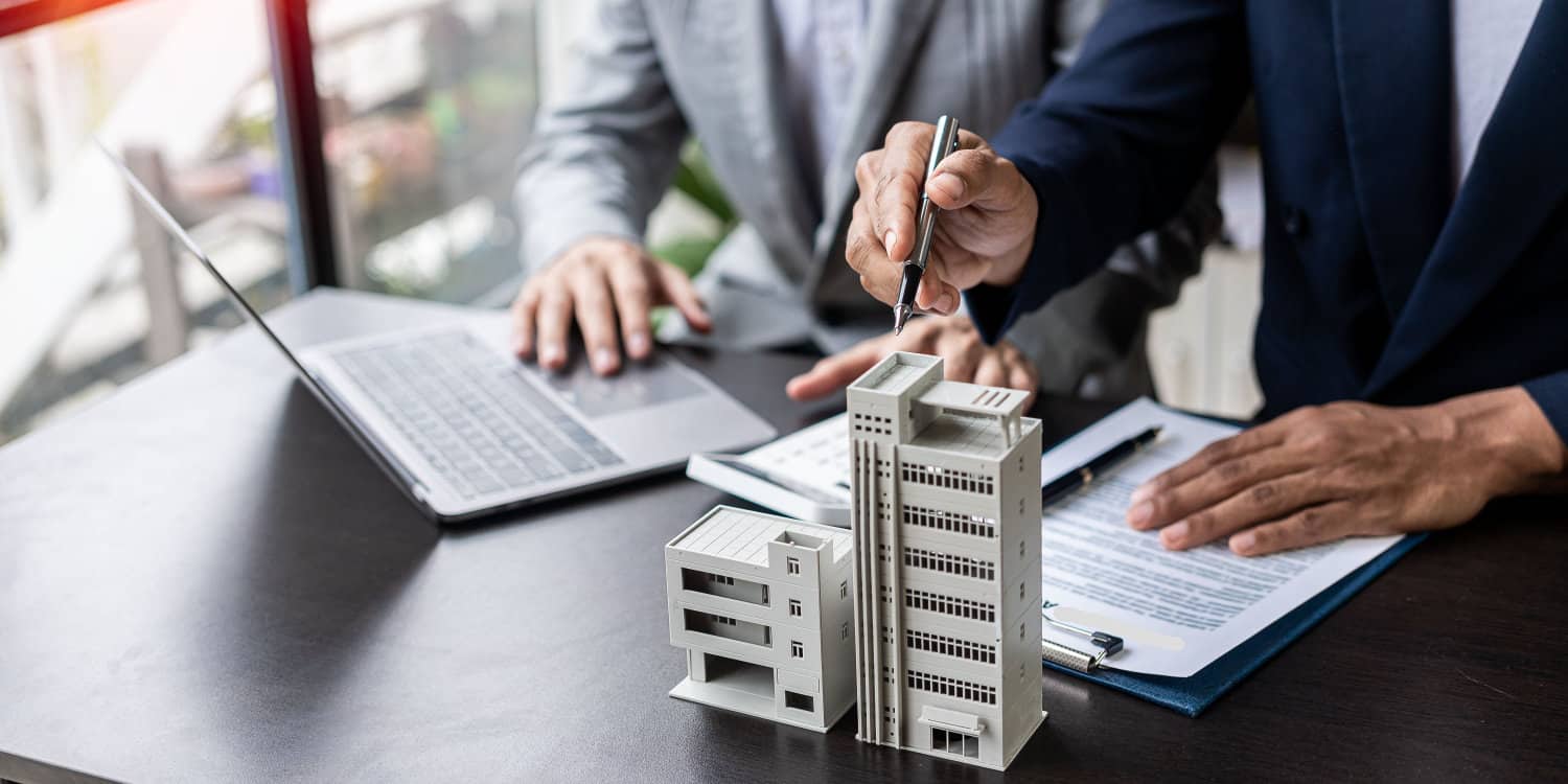 Property professionals standing at a desk, calculating business rates with a laptop and model of an office building sitting on the desk.