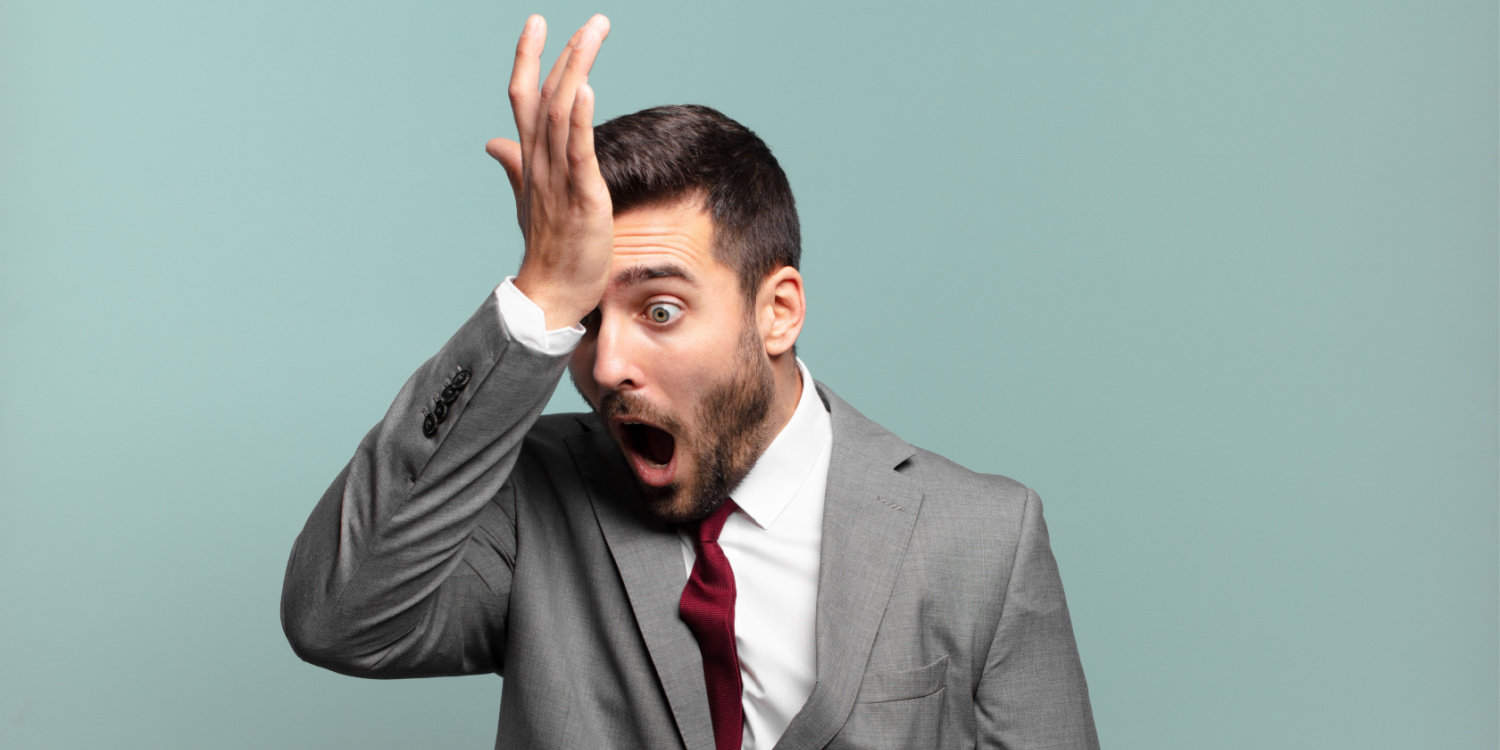 Young entrepreneur raising his palm to his forehead thinking oops, after making a stupid business mistake.