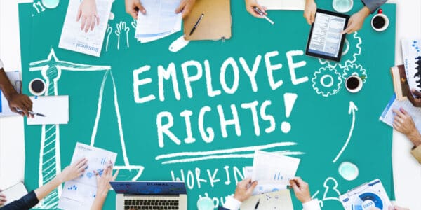 Overhead view of people working at a green table with the words 'EMPLOYEE RIGHTS!' displayed on the table surface. Employment Law concept image.