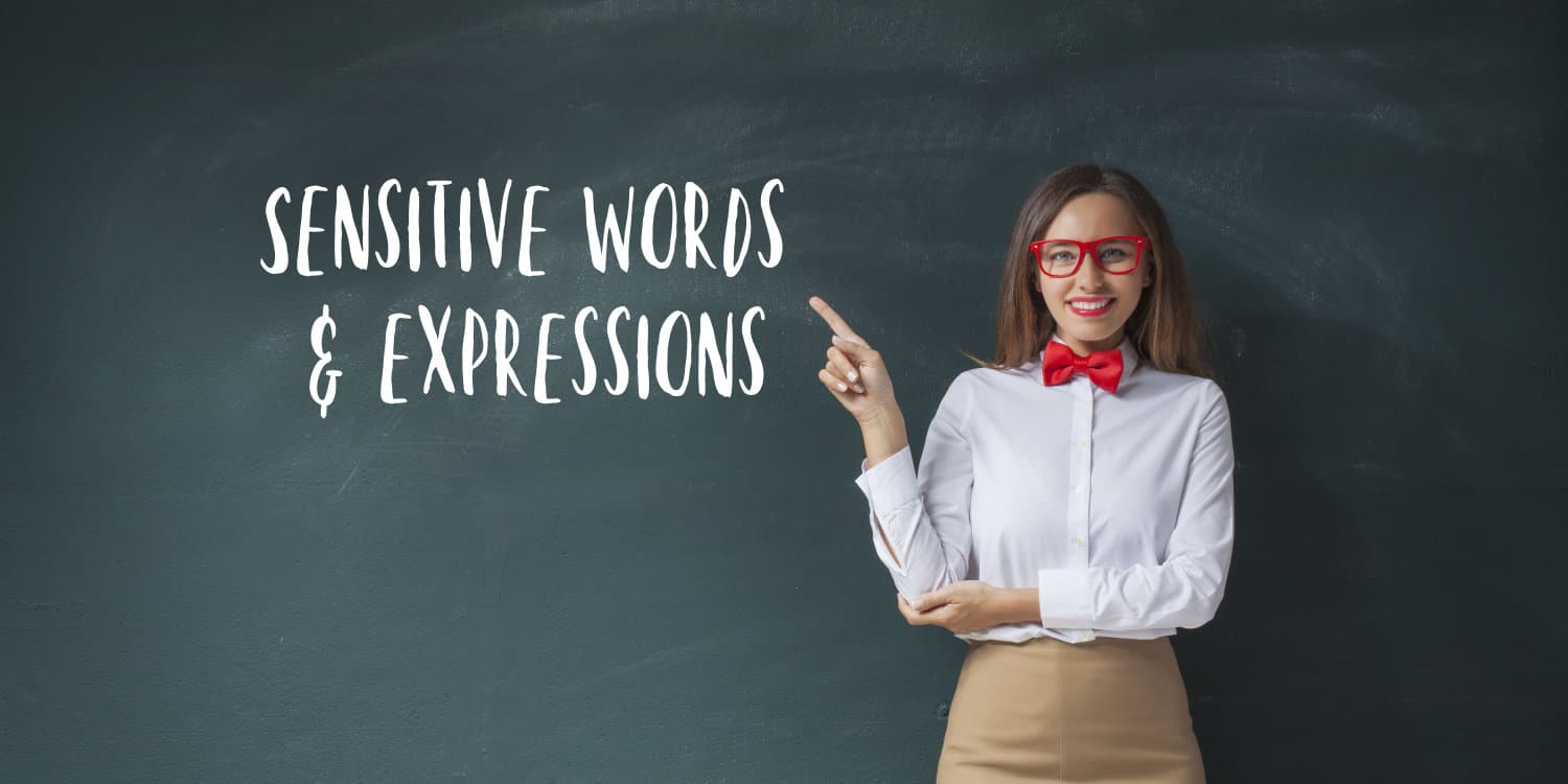 Young woman wearing white shirt with red bowtie, pointing at the words 'SENSITIVE WORDS & EXPRESSIONS' written in white chalk on a blackboard.