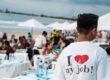 A young man wearing a T-shirt "I love my job" while working at a holiday beach club.