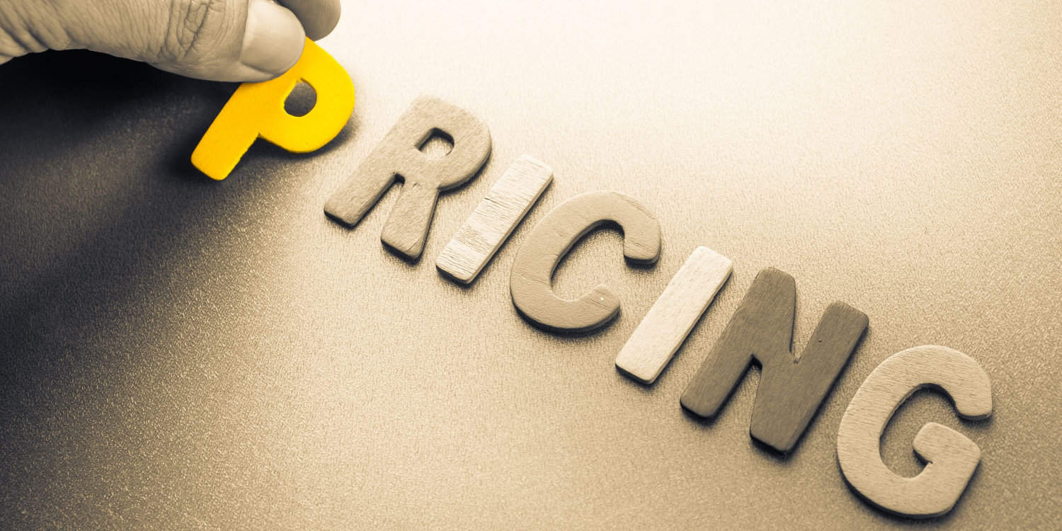 Hand arranging wood letters as 'Pricing' word.