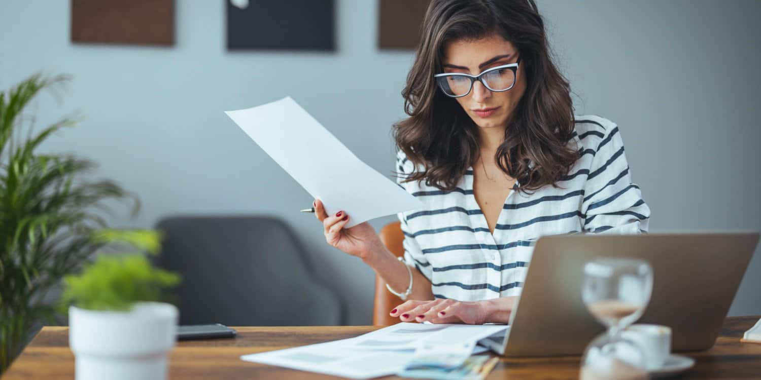 A smart business woman sitting at her desk with tax papers and a laptop, preparing her company for the new tax year 2024/25.