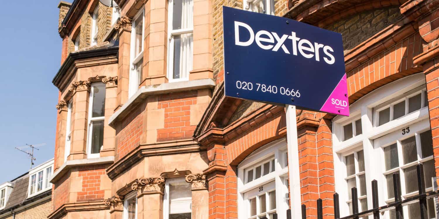 Estate agent SOLD sign outside a row of Victorian terraced houses in London.