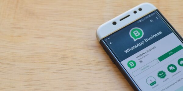 WhatsApp Business app displayed on a smartphone lying on a wooden desktop.