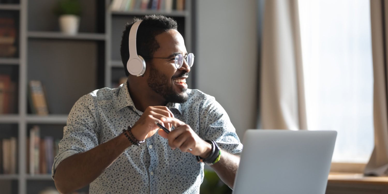 Millennial entrepreneur smiling and working at his desk.