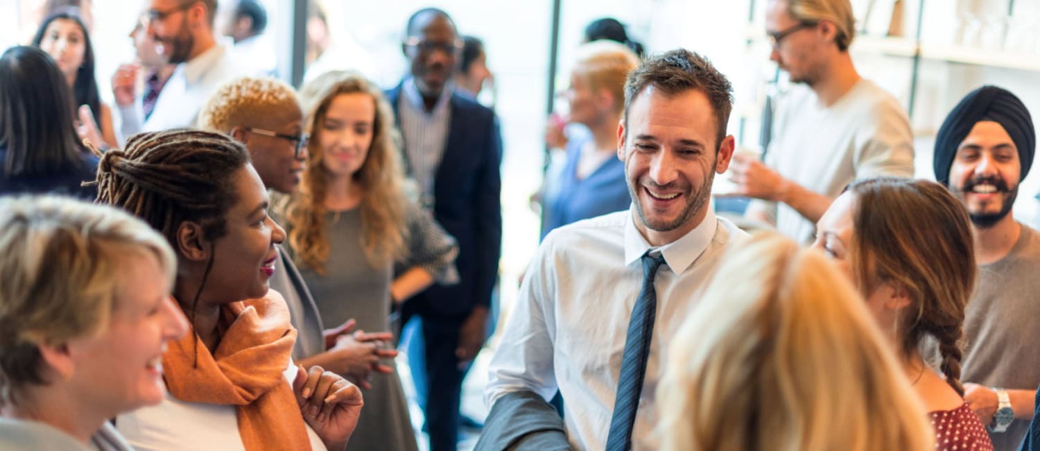 A lively gathering of diverse people engaged in conversation at a bright, modern venue.