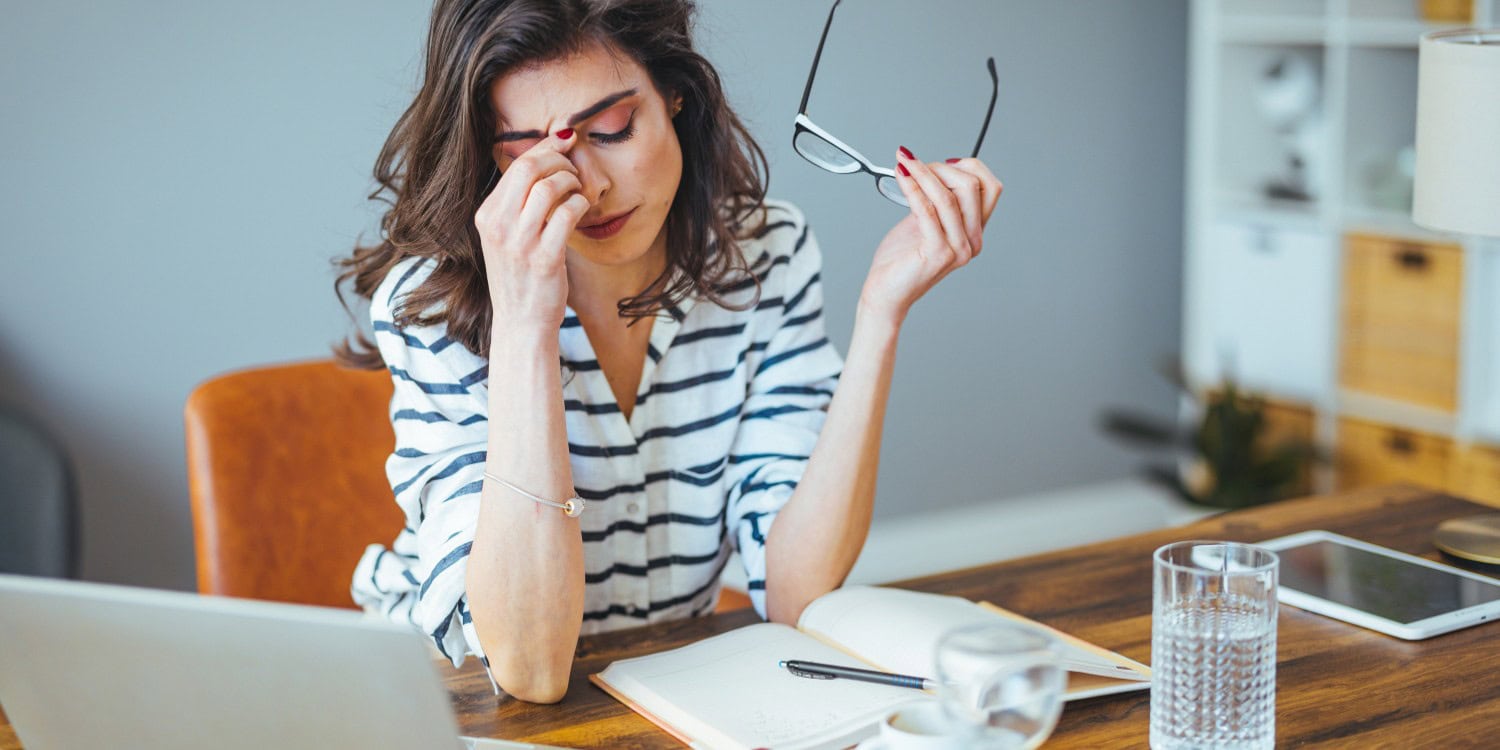 A woman sitting at her desk and looking tired and burnt out.