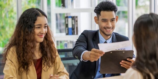 A startup hiring team interviews a job candidate, with a smiling interviewer holding a resume during the interview process