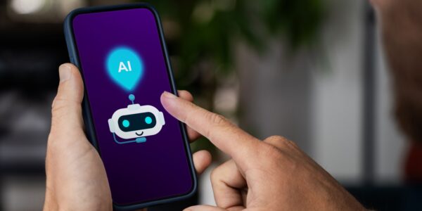 Person holding a smartphone with a screen displaying a cute robot icon and "AI" text, representing the use of AI agents on mobile devices