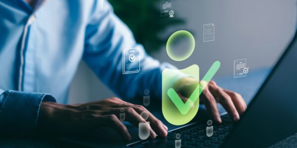 Person typing on a laptop with digital verification icons floating on screen, representing the process of Companies House identity verification for UK company directors and PSCs