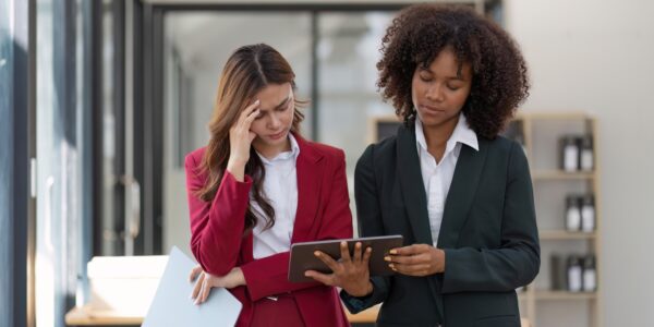 Two businesswomen reviewing concerning company documents on tablet