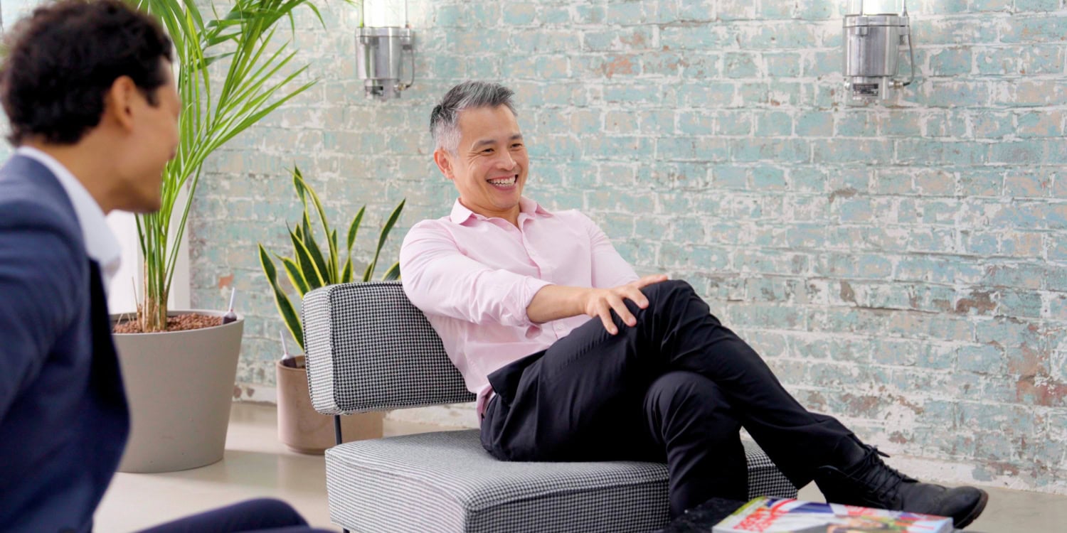 Two professionals chatting in a relaxed serviced office lounge with modern seating.