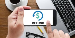 Image of a person holding a mobile phone with the screen displaying the dollar sign and the word 'REFUND'.